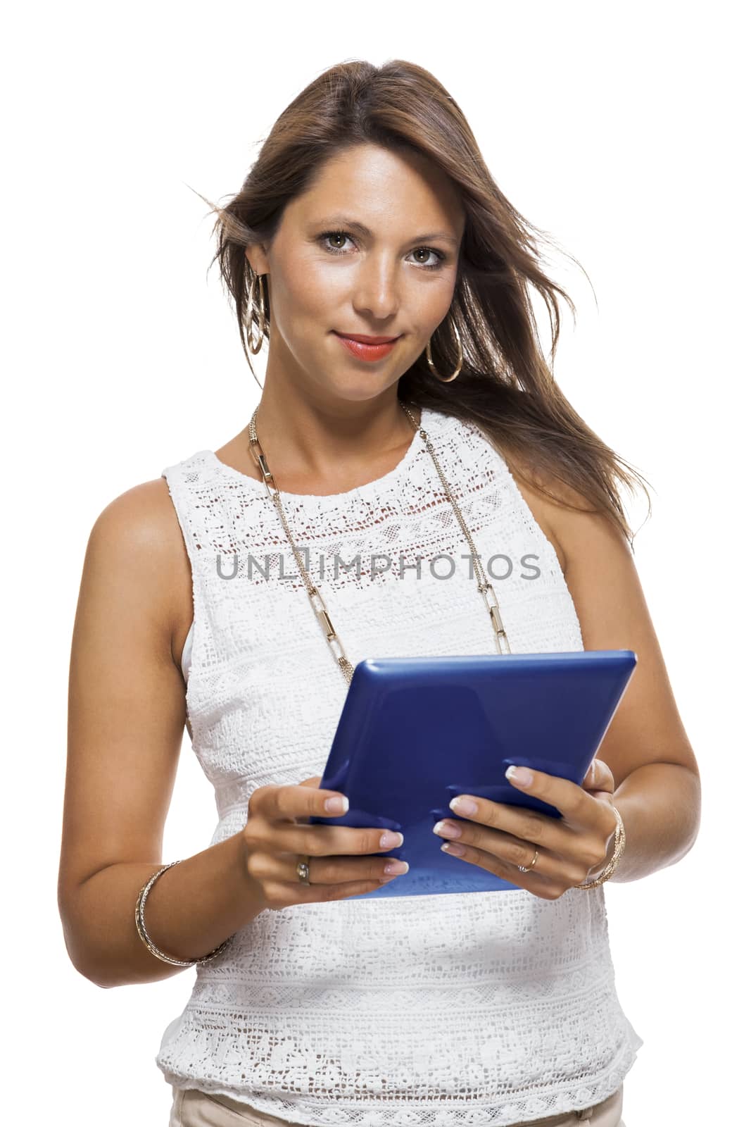 Attractive young business woman standing chatting on a mobile while simultaneously reading a tablet computer with a smile, isolated on white