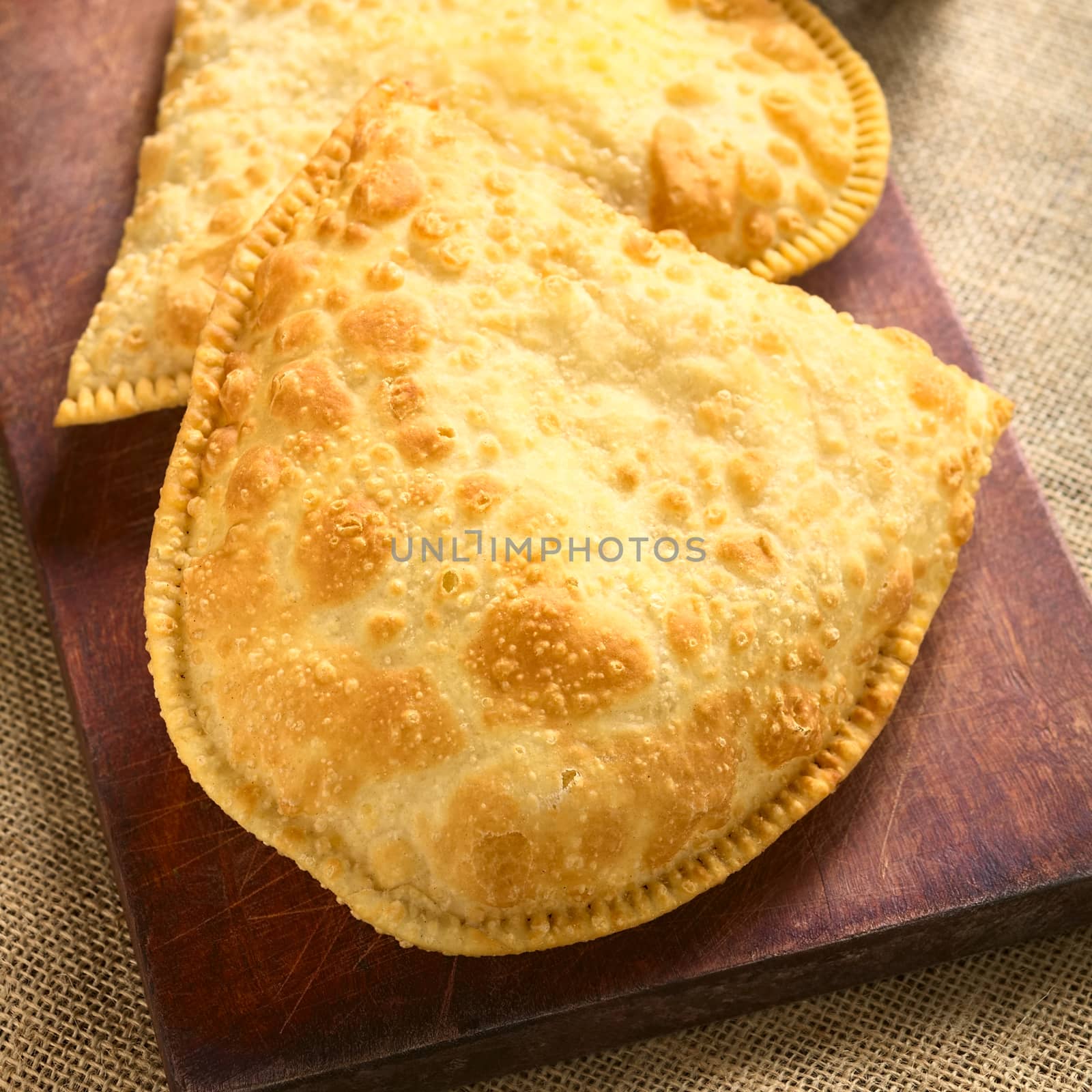Traditional Bolivian Pastel, a deep-fried pastry filled with cheese, which is a popular street snack, photographed with natural light (Selective Focus, Focus on the lower half of the pastel)