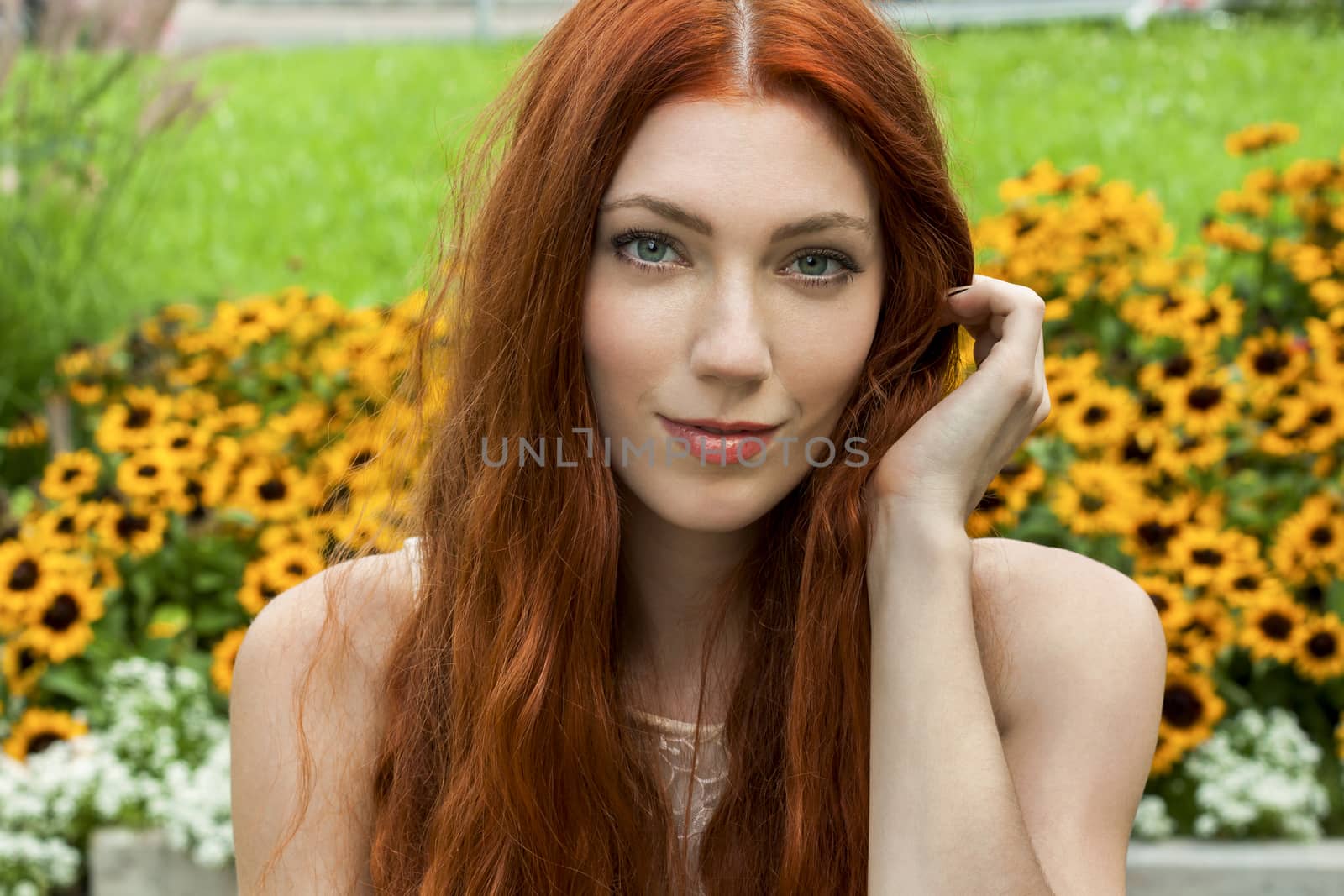 Close up Young Woman with long red Hair Relaxing at the Garden While Looking Afar