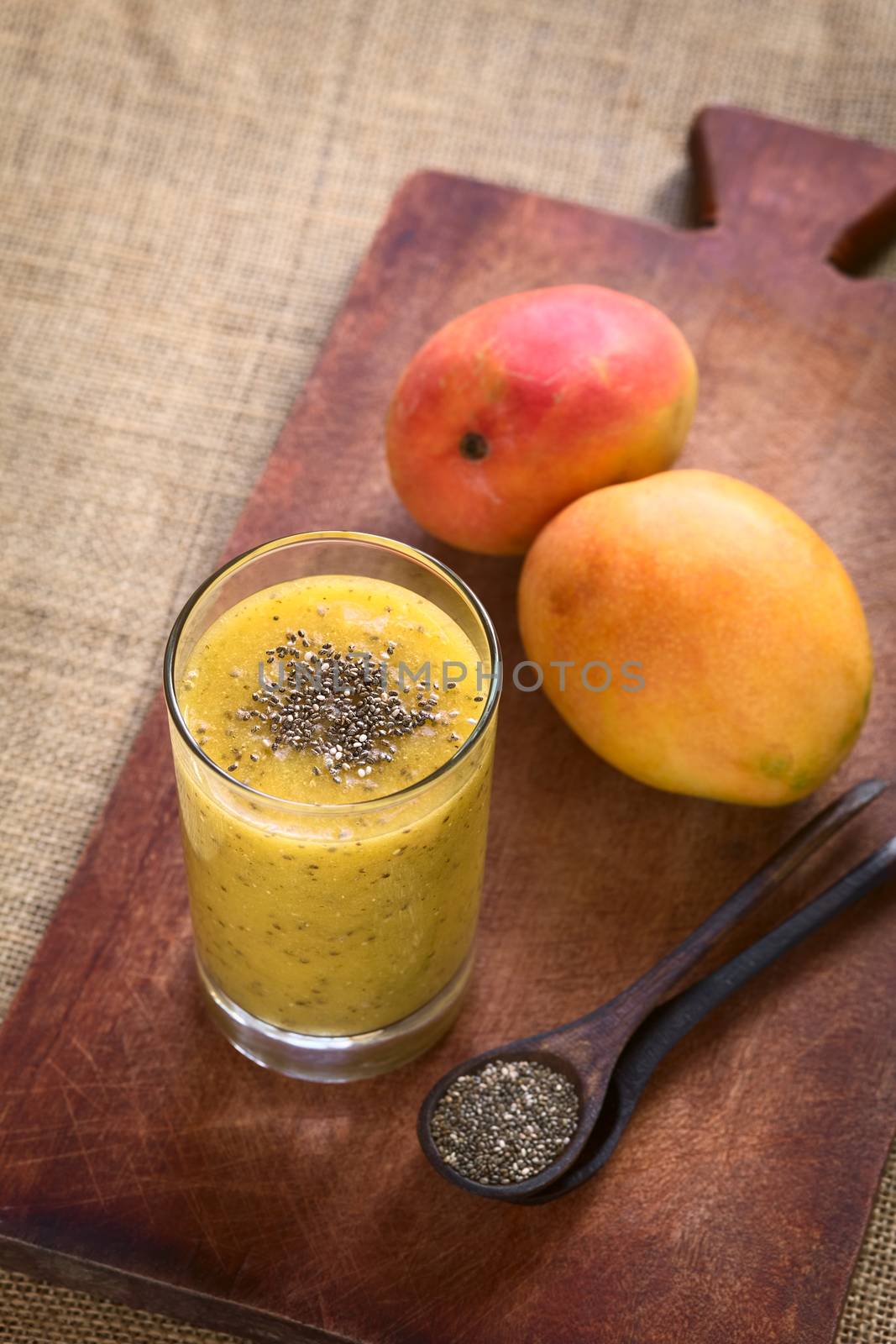 Chia seed (lat. Salvia hispanica) and mango juice photographed on wood with natural light. Chia seeds are considered a superfood containing proteins, omega fats, minerals and antioxidants (Selective Focus, Focus on the chia seeds on the juice)