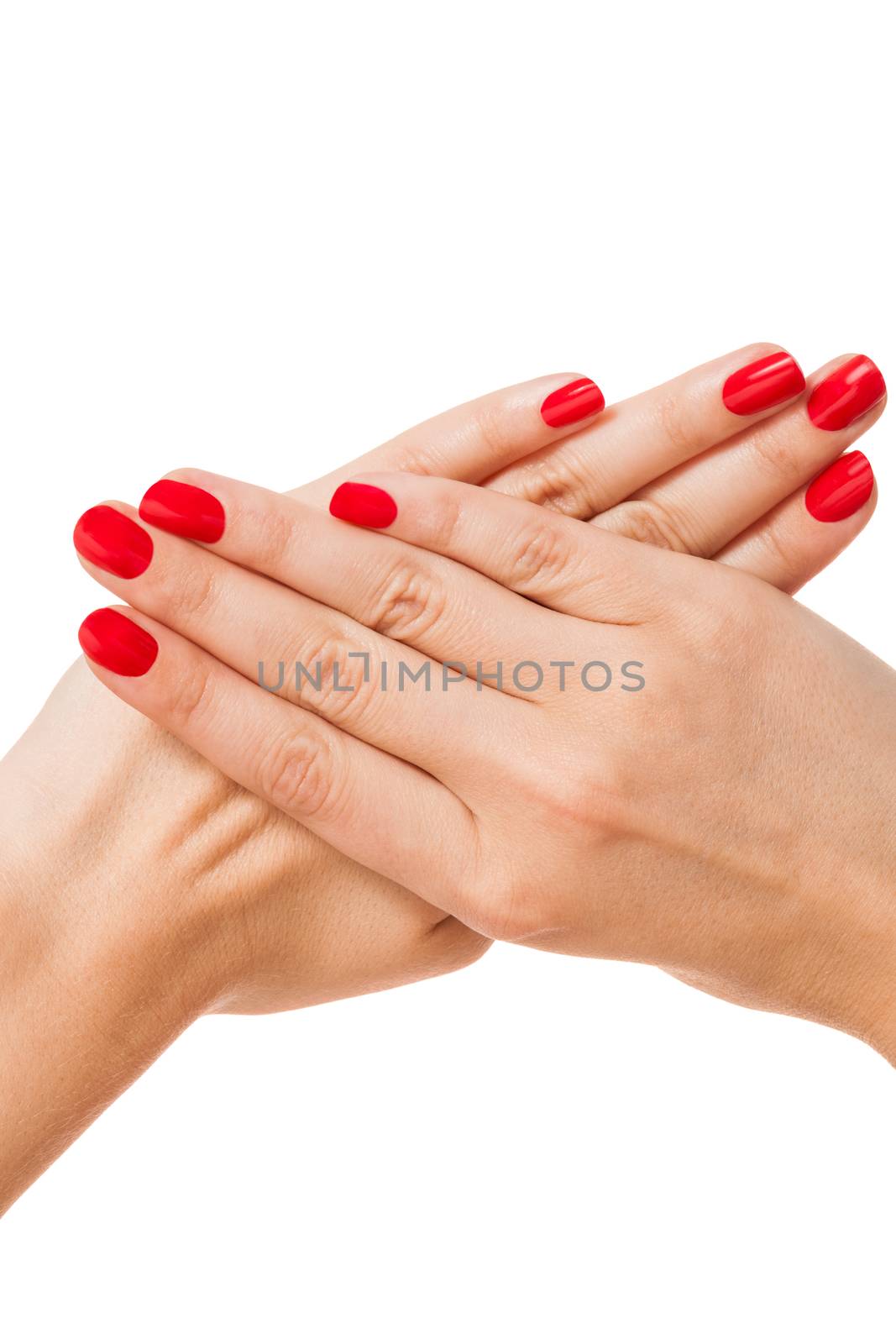 Woman with beautiful manicured red fingernails gracefully crossing her hands to display them to the viewer on a white background in a fashion, glamour and beauty concept