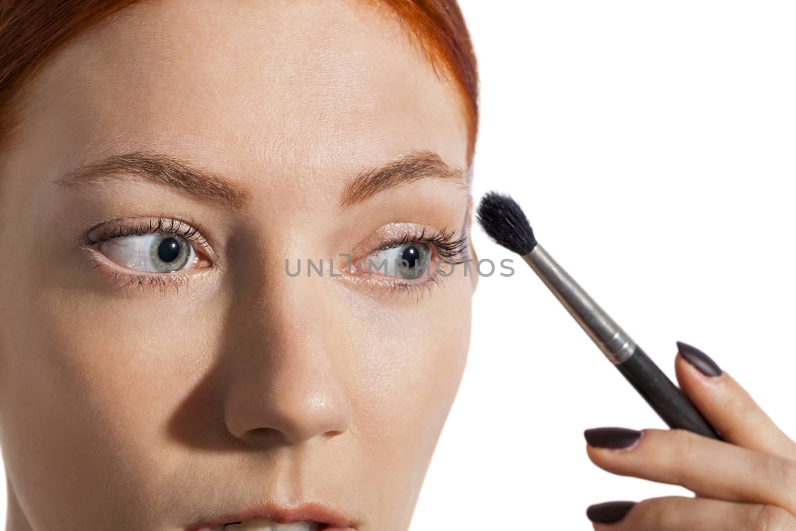 Close up Pretty Woman Applying Eye Shadow Makeup Using Brush on White Background.