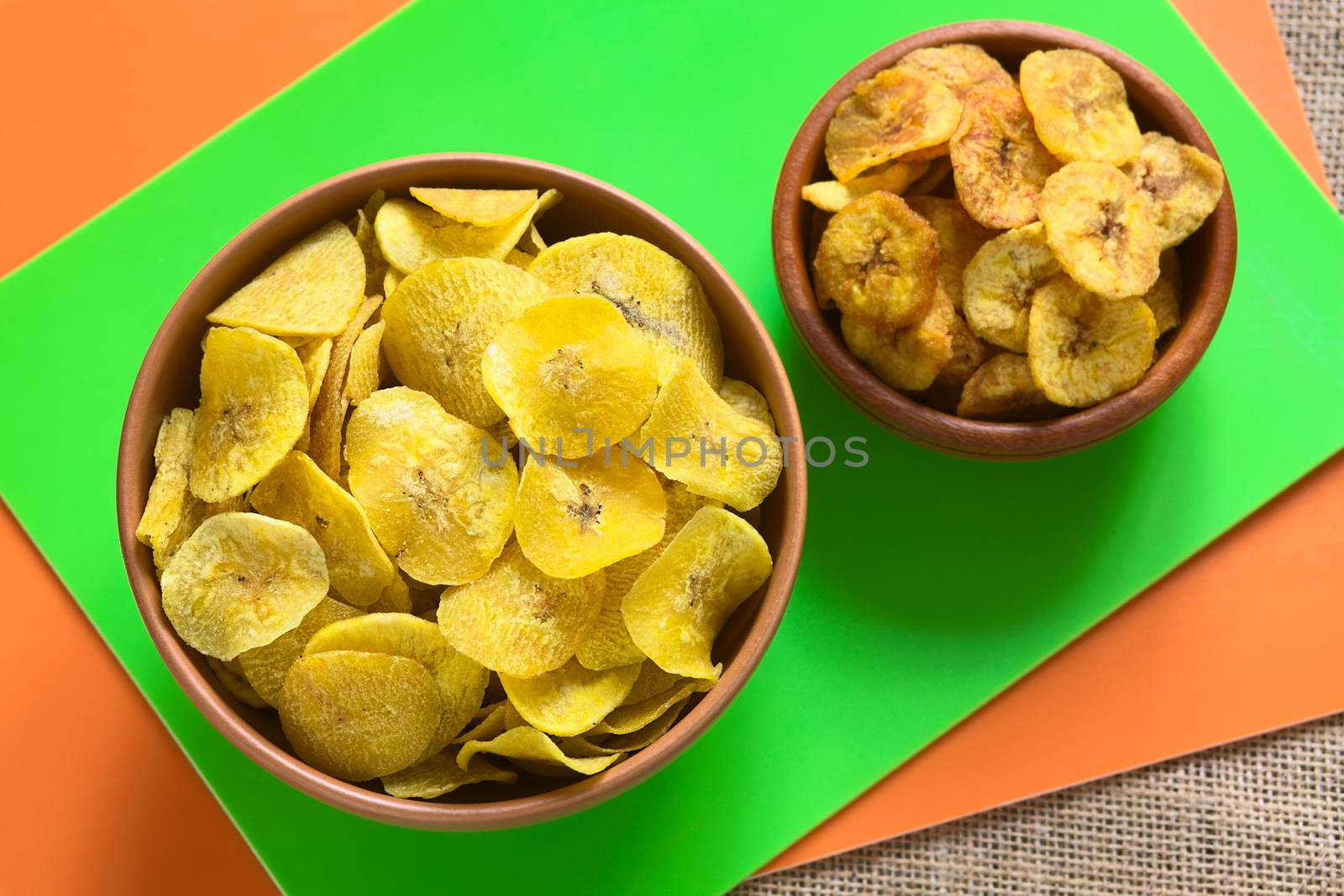 Overhead shot of salty (left) and sweet (right) plantain chips in bowls, a popular snack in South America photographed with natural light (Selective Focus, Focus on the salty chips) 