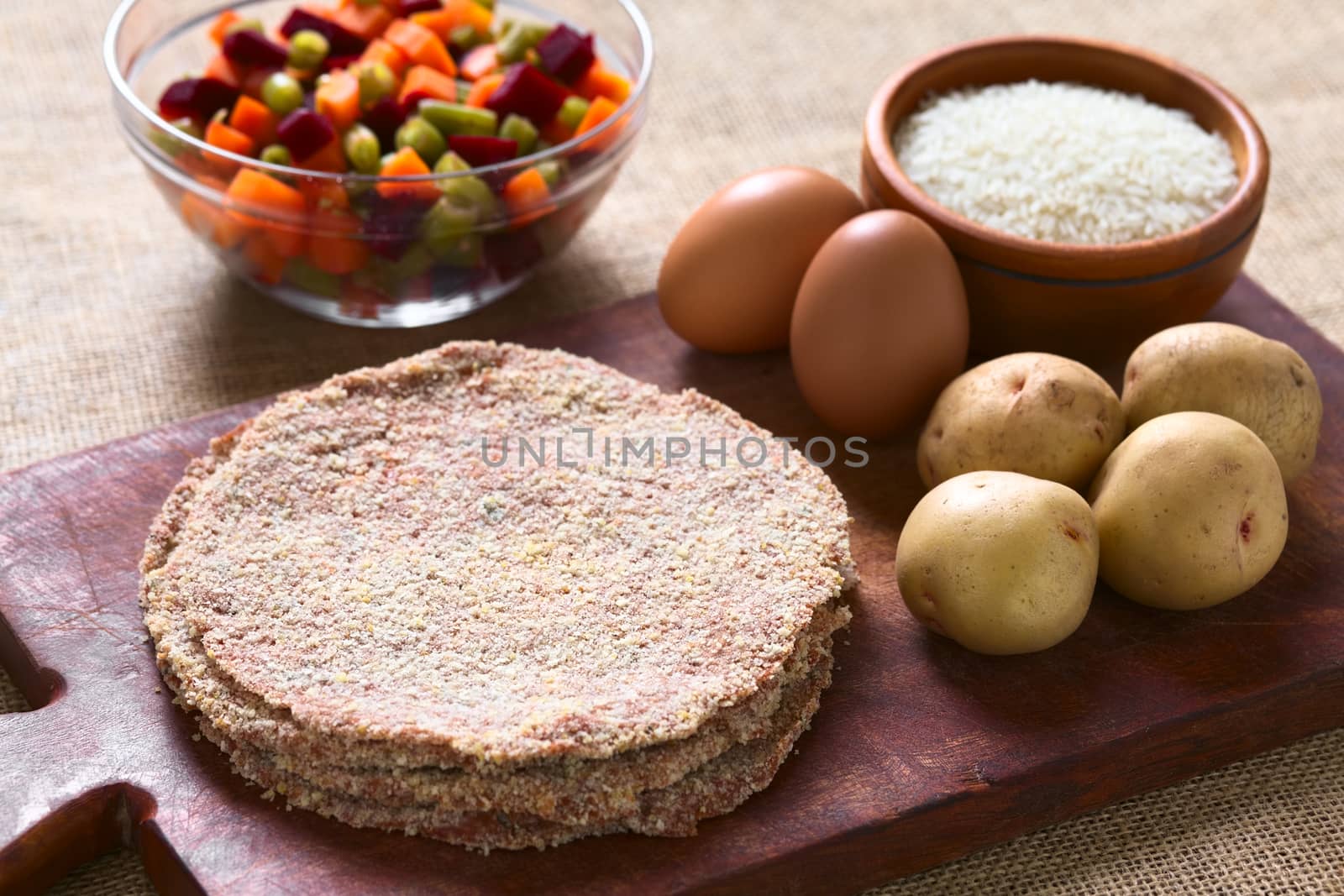 Traditional Bolivian meat called Silpancho, which is a breaded flat, round piece of beef meat, served with fried egg, rice, fried potatoes and vegetables (carrot, bean, beetroot), photographed with natural light (Selective Focus, Focus one third into the meat)