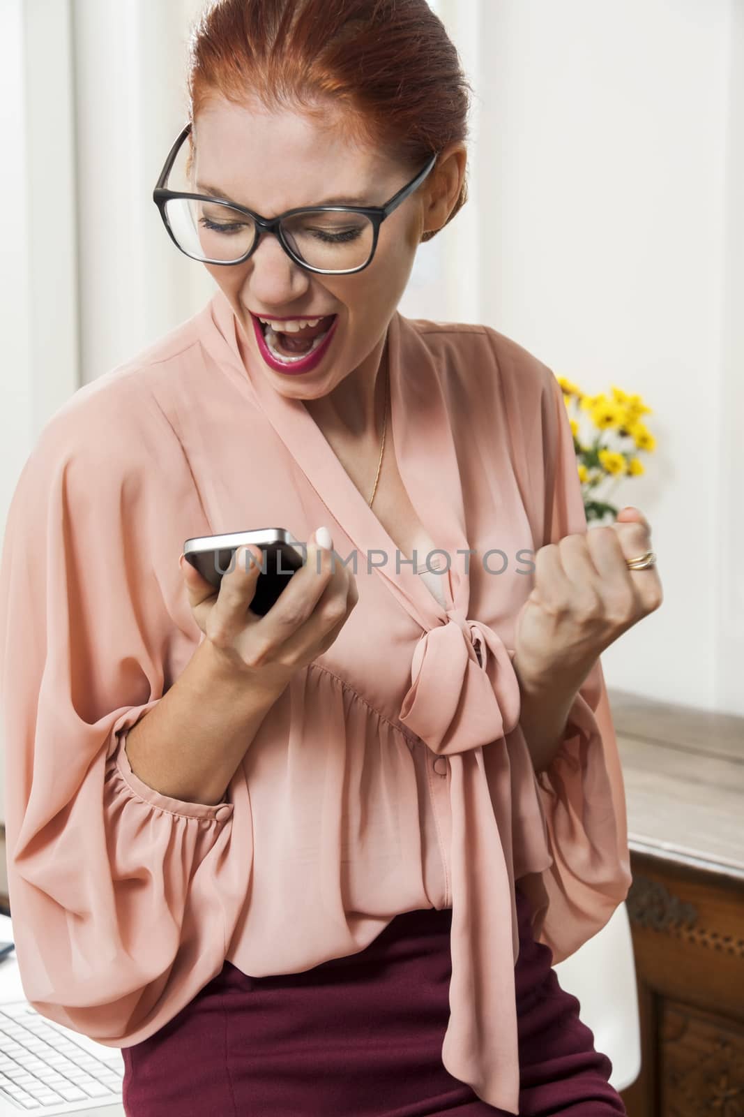 Young Serious Office Woman Talking to Someone Though Mobile Phone While Sitting on the Table.