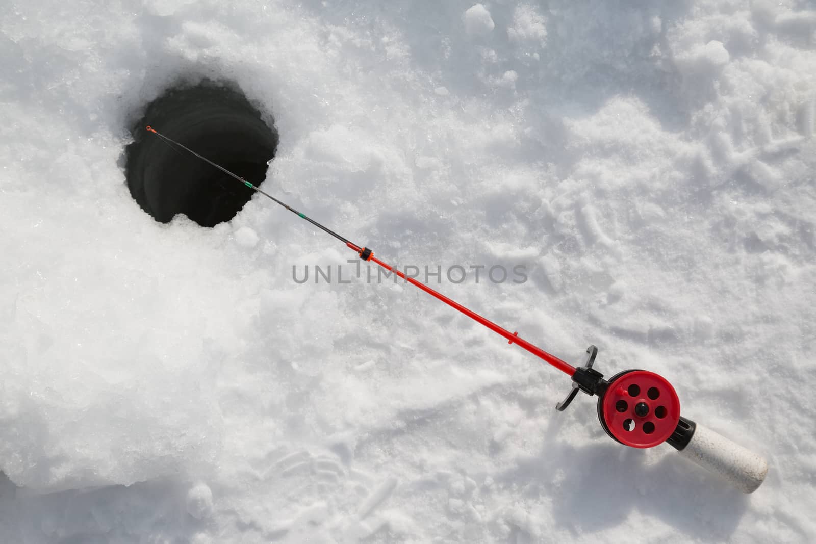 Winter fishing rod in the hole in the snow
