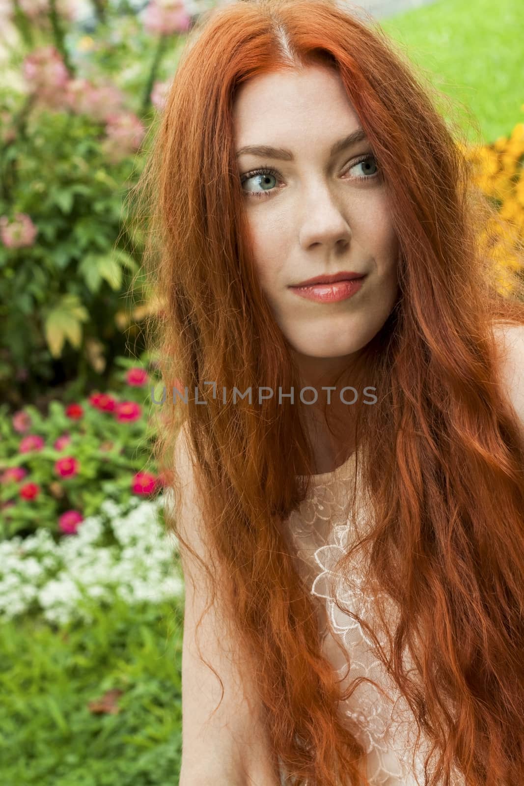 Close up Young Woman with long red Hair Relaxing at the Garden While Looking Afar