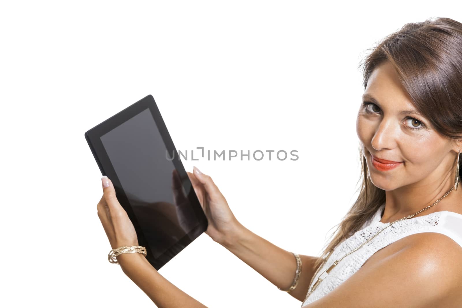 Attractive young business woman standing chatting on a mobile while simultaneously reading a tablet computer with a smile, isolated on white