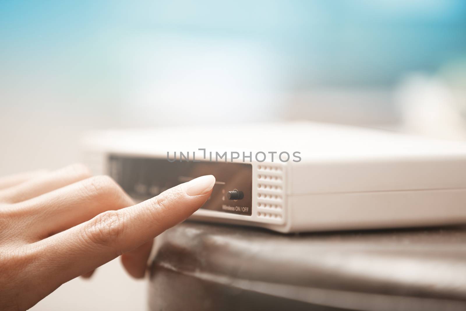 Human hand turning on wireless modem. Close-up horizontal photo