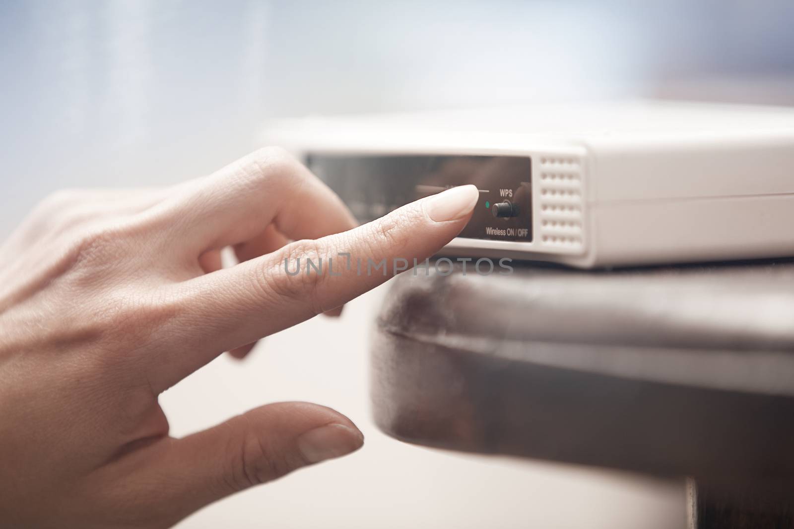 Human hand turning on wireless modem. Close-up horizontal photo