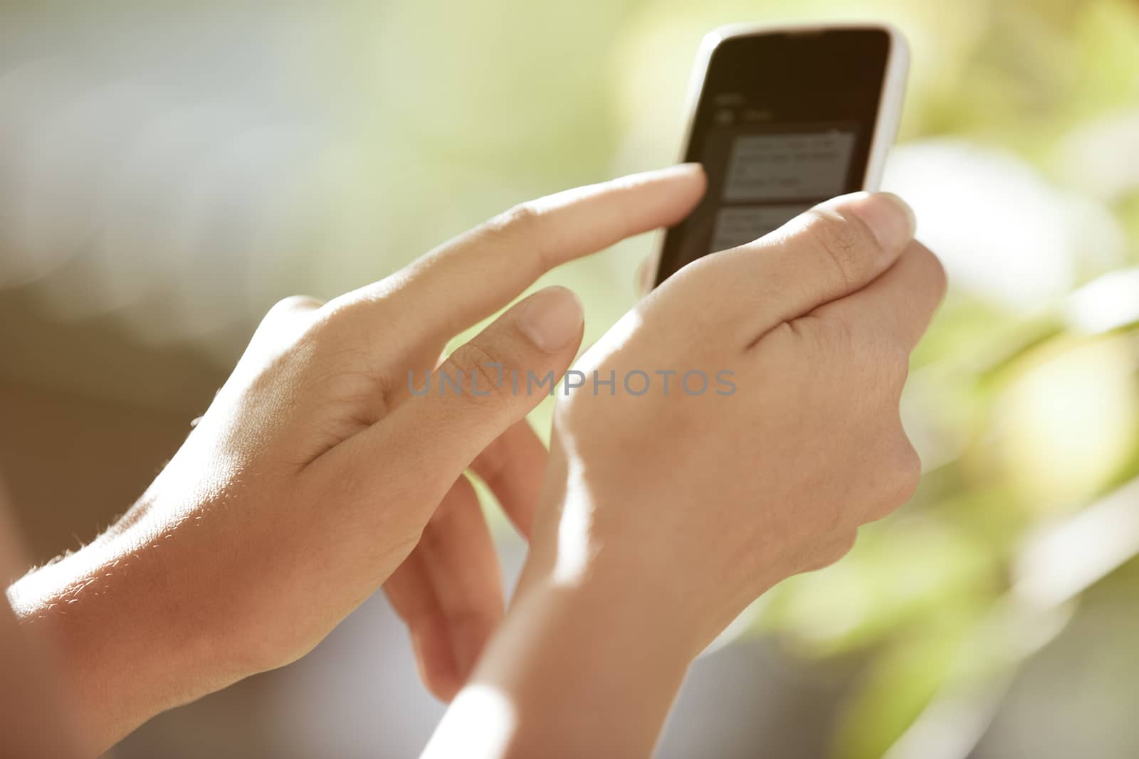 Hands of woman with smartphone in the garden