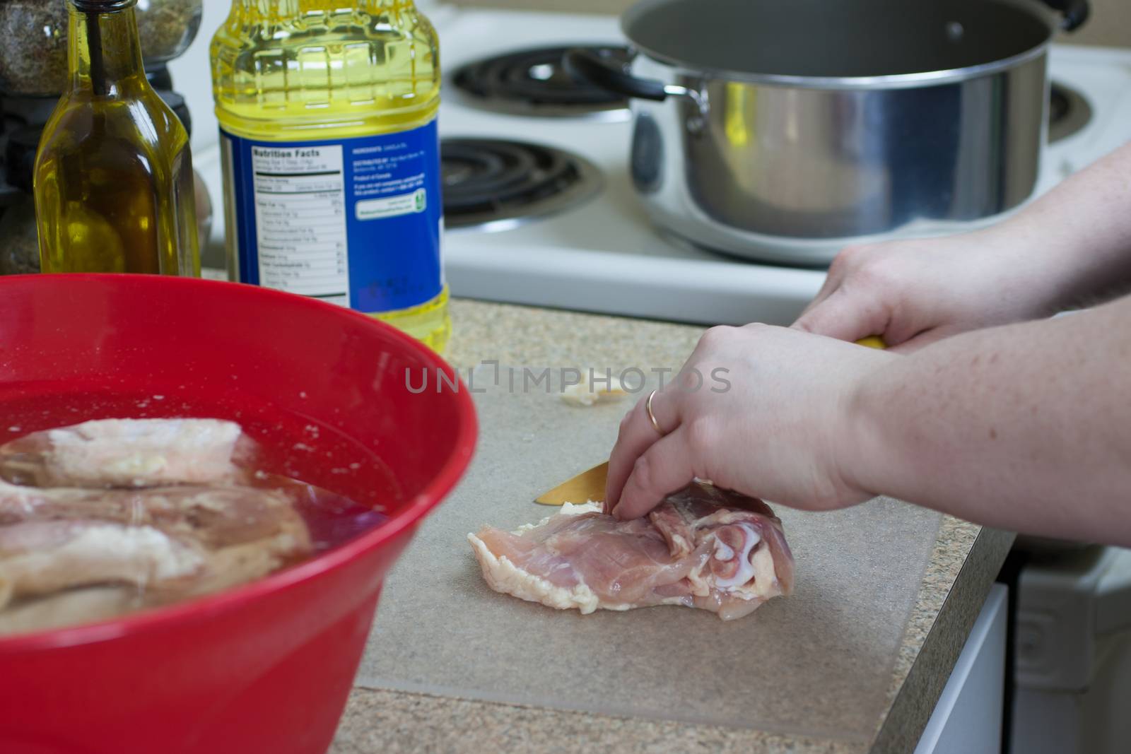 A woman trims and prepares fresh chicken for frying.