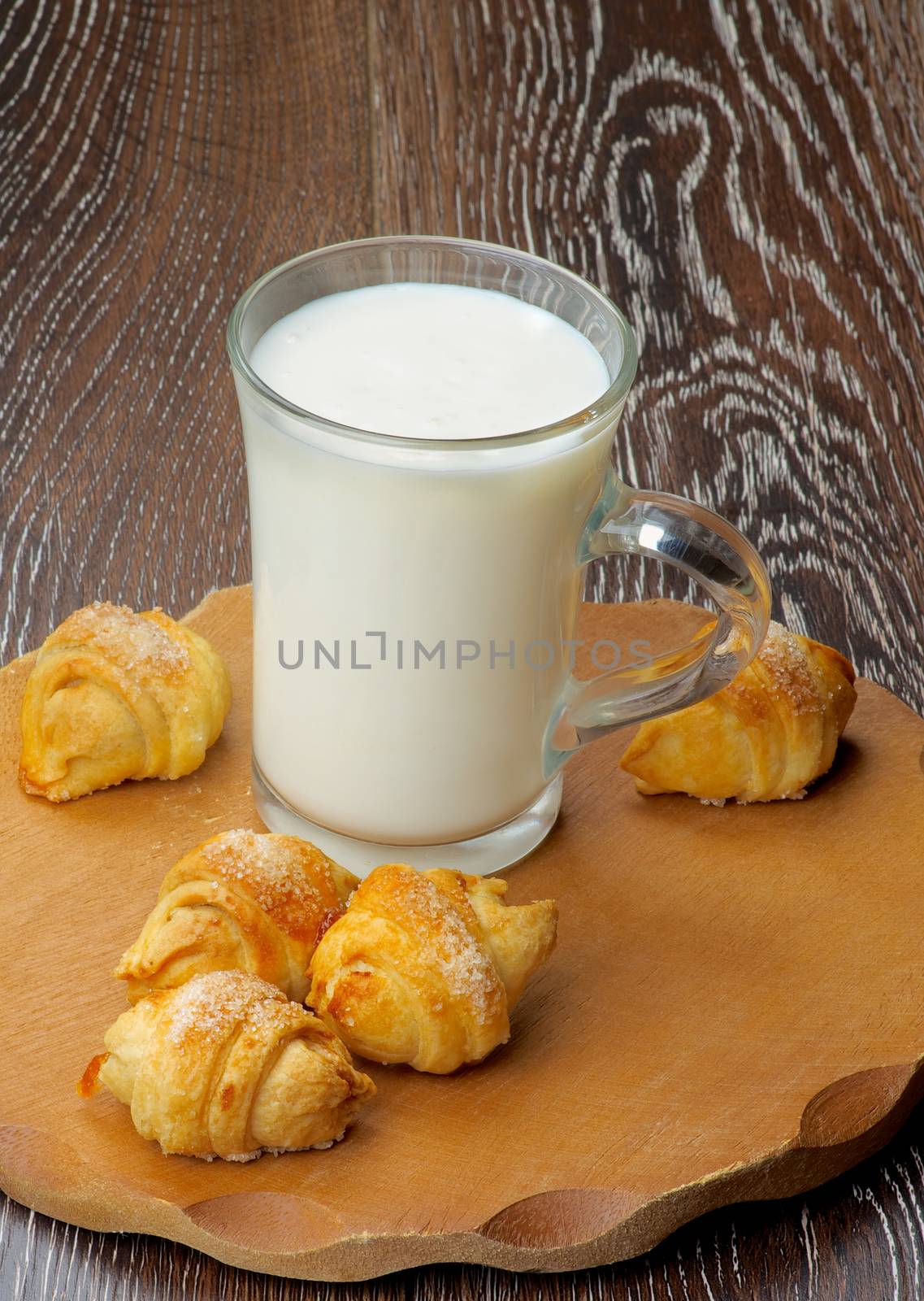 Arrangement of Croissant Cookies with Jam  and Glass Cup of Milk on Wooden Plate closeup on Rustic Wooden background