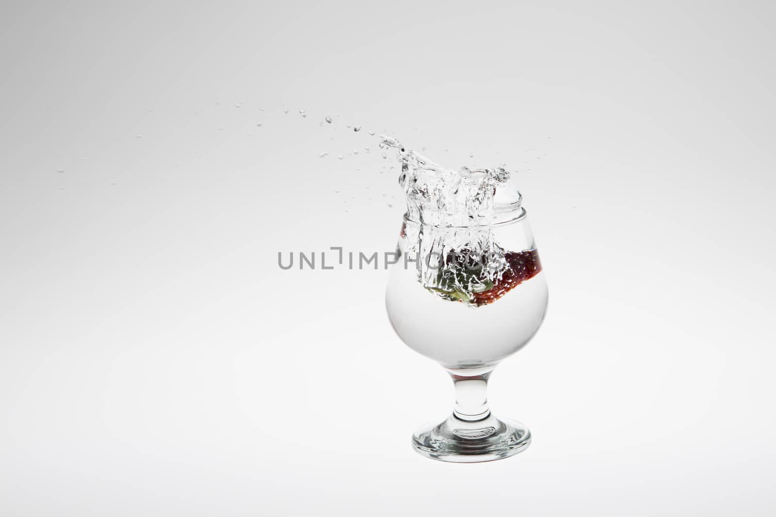 Red strawberry inside flowing water on white background