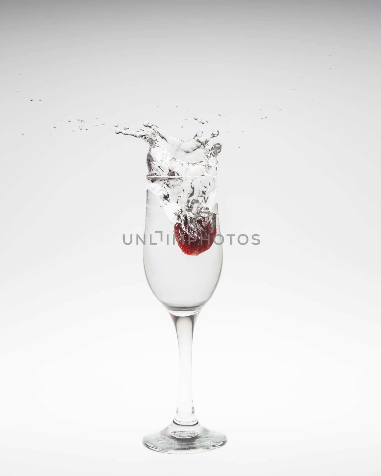 Close-up image of strawberry dropped to water on white background