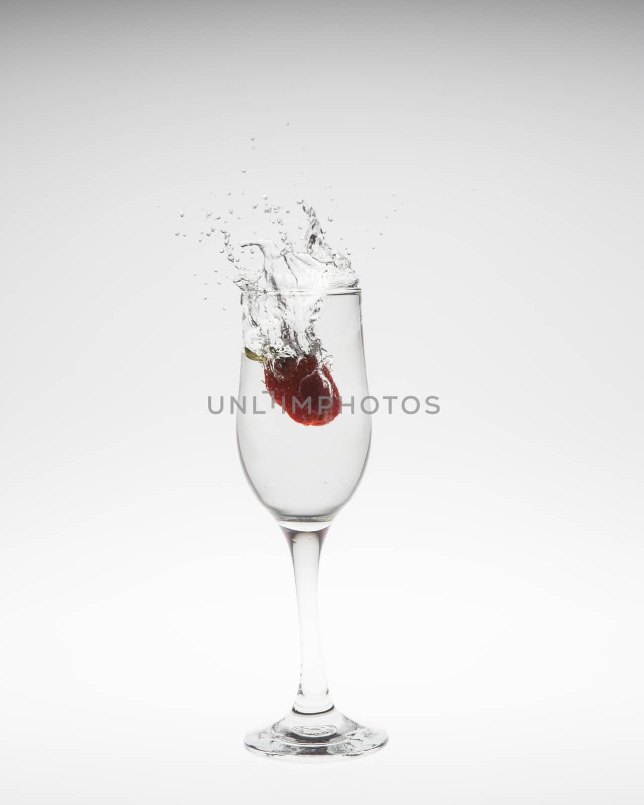 fresh strawberry dropped into water with splash on white backgrounds