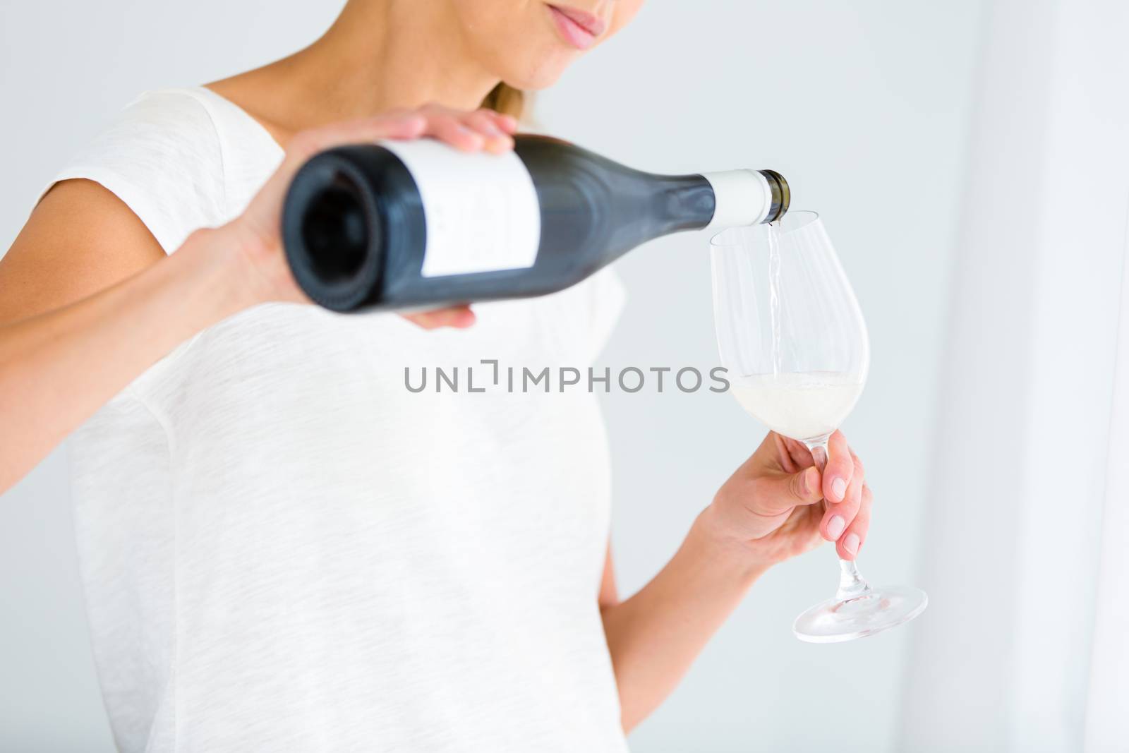 Gorgeous young woman with a glass of wine, pouring herself a glass of wine (shallow DOF; color toned image)