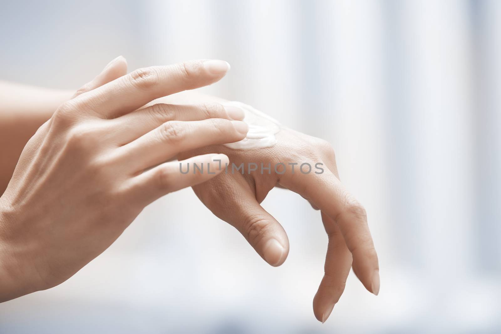 Woman applying moisturizing cream on hands