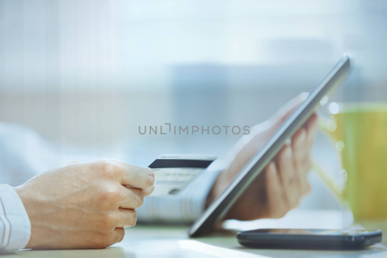 Human hands with tablet PC and credit card behind the office glass