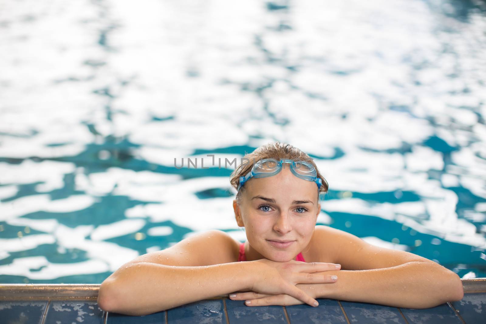 Female swimmer in an indoor swimming pool - looking at the camera, looking content after a good swim (shallow DOF)