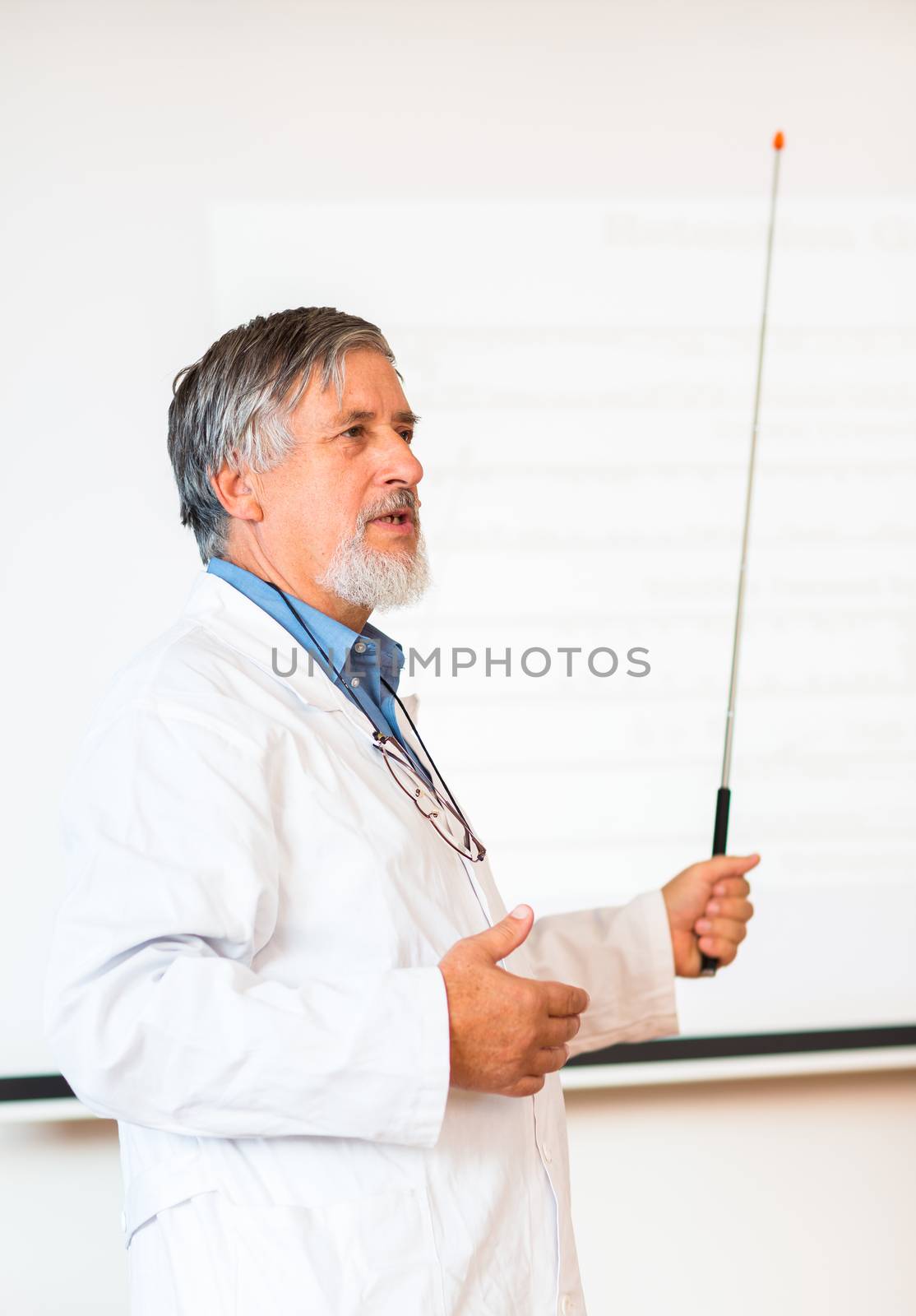 Senior chemistry professor giving a lecture in front of classroom full of students (shallow DOF; color toned image)