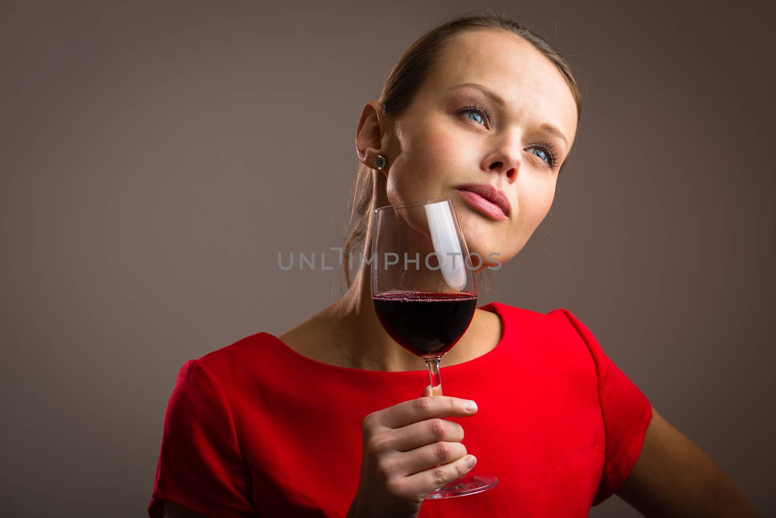 Elegant young woman in a red dress, having a glass of red wine by viktor_cap