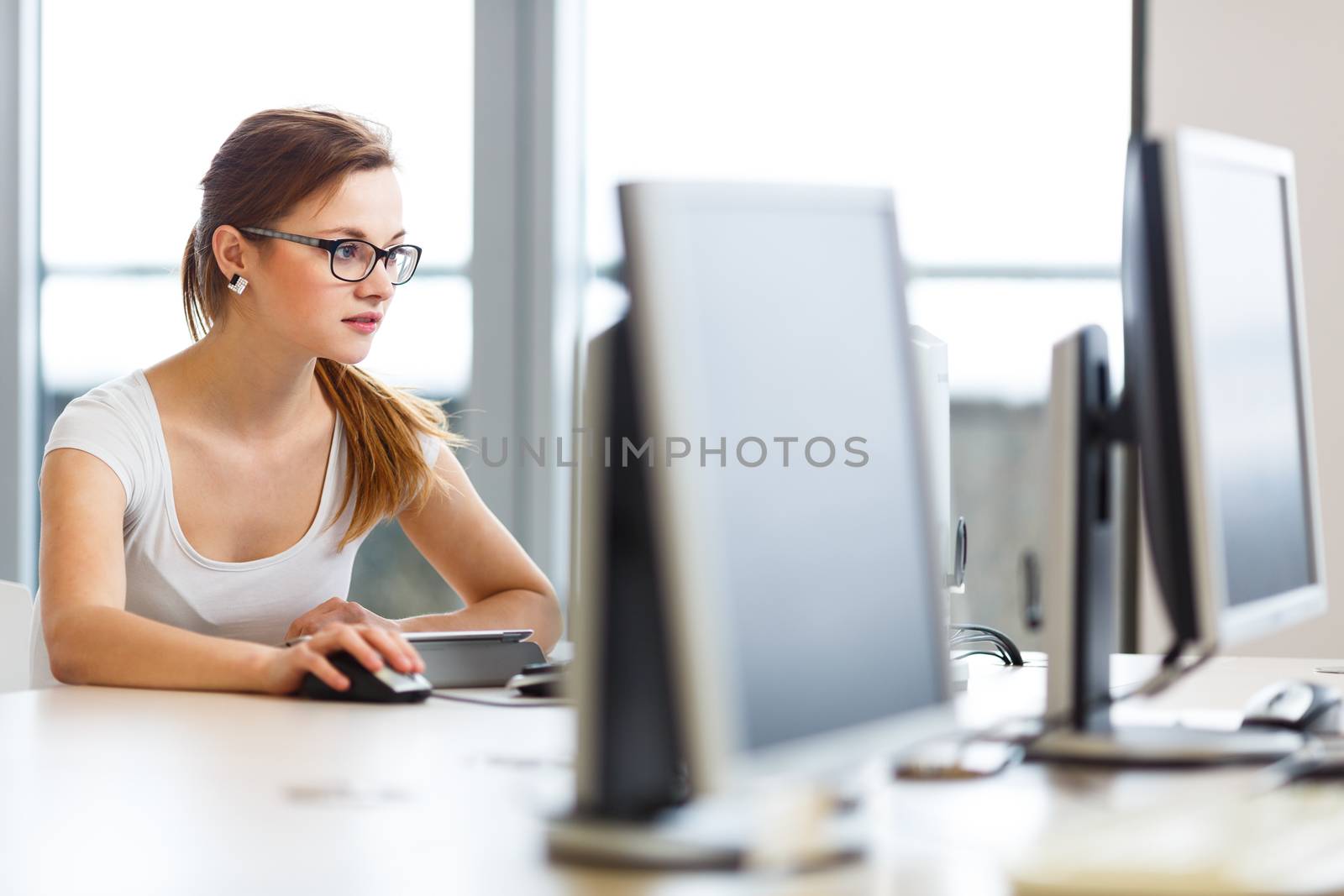 Pretty, female student looking at a desktop computer screen by viktor_cap