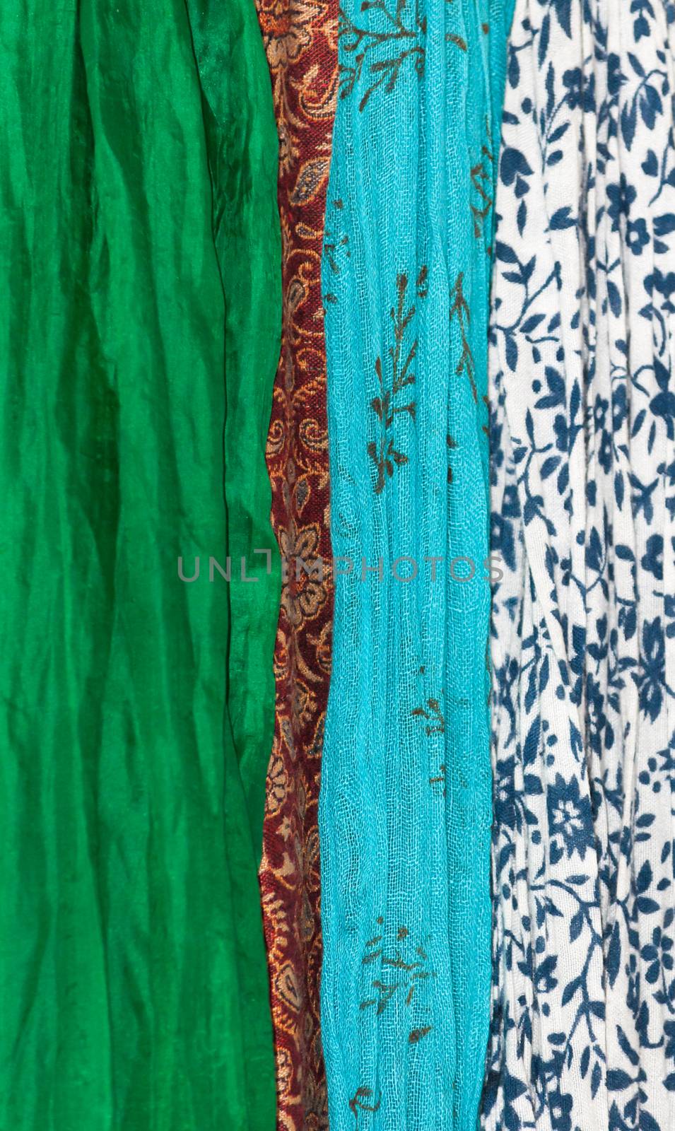Fabrics vertical. Assortment of fabrics in organic theme - green silk, red indian wool, turquoise gauzy cotton and white cotton with marine blue floral.