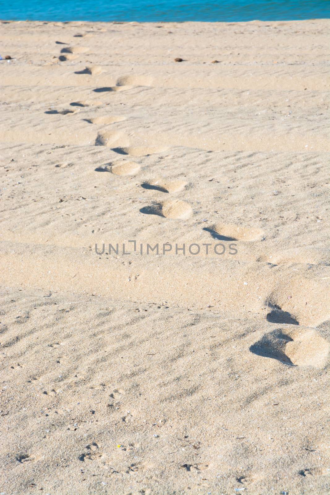 Sand tracks and footprints into the water. Mallorca, Balearic islands, Spain.