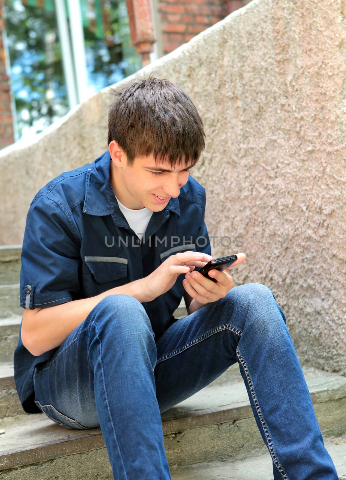 Cheerful Teenager with Cellphone on the landing steps