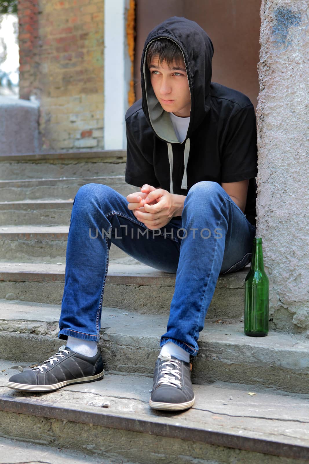 Sad Teenager on the landing steps with a Bottle of the Beer