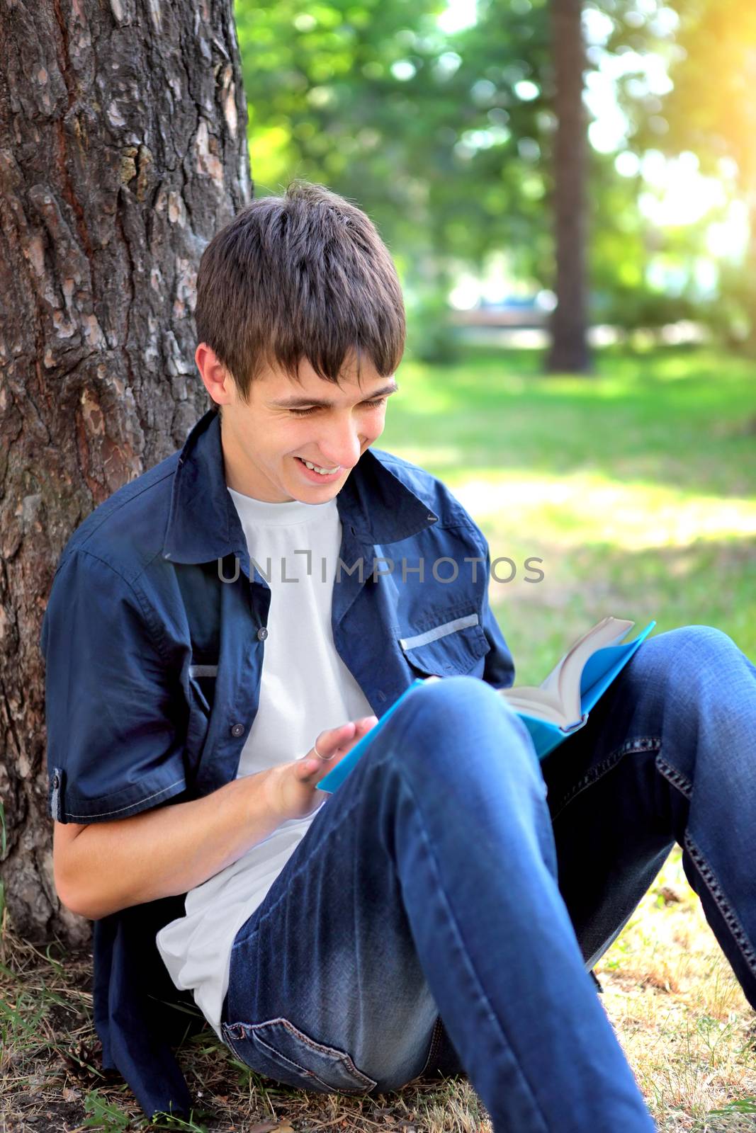 Cheerful Teenager with the Book under the Tree in the Summer Park