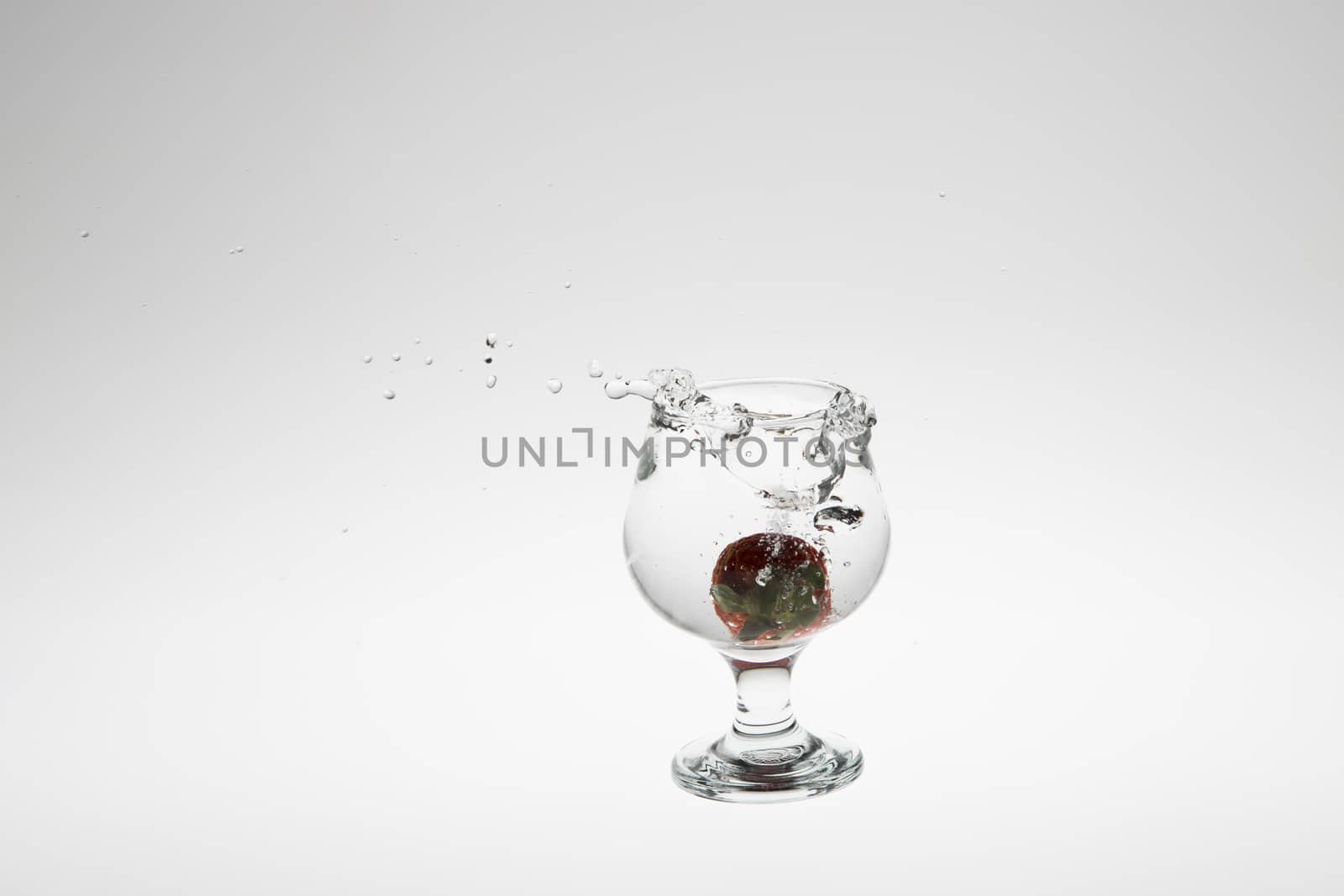 Red strawberry inside flowing water on white background