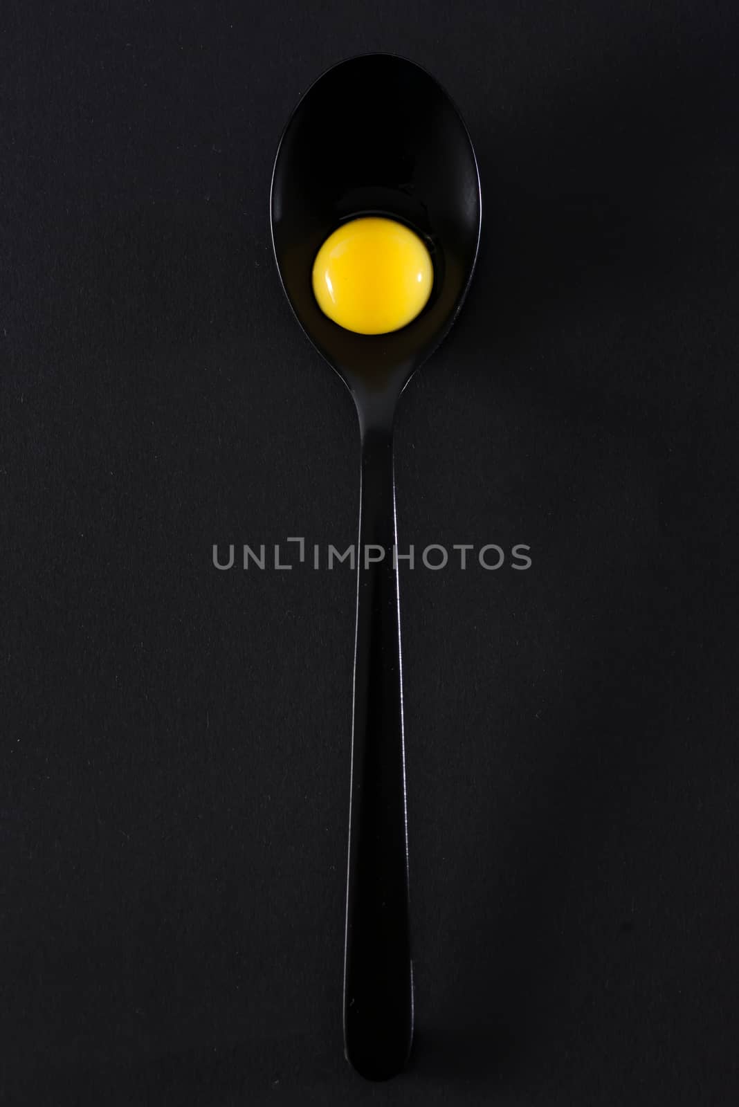 Quail eggs in spoon on black background