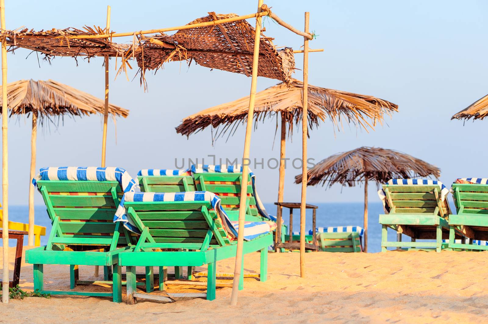 Beach umbrellas and deckchair on the tropical coast in Goa, india