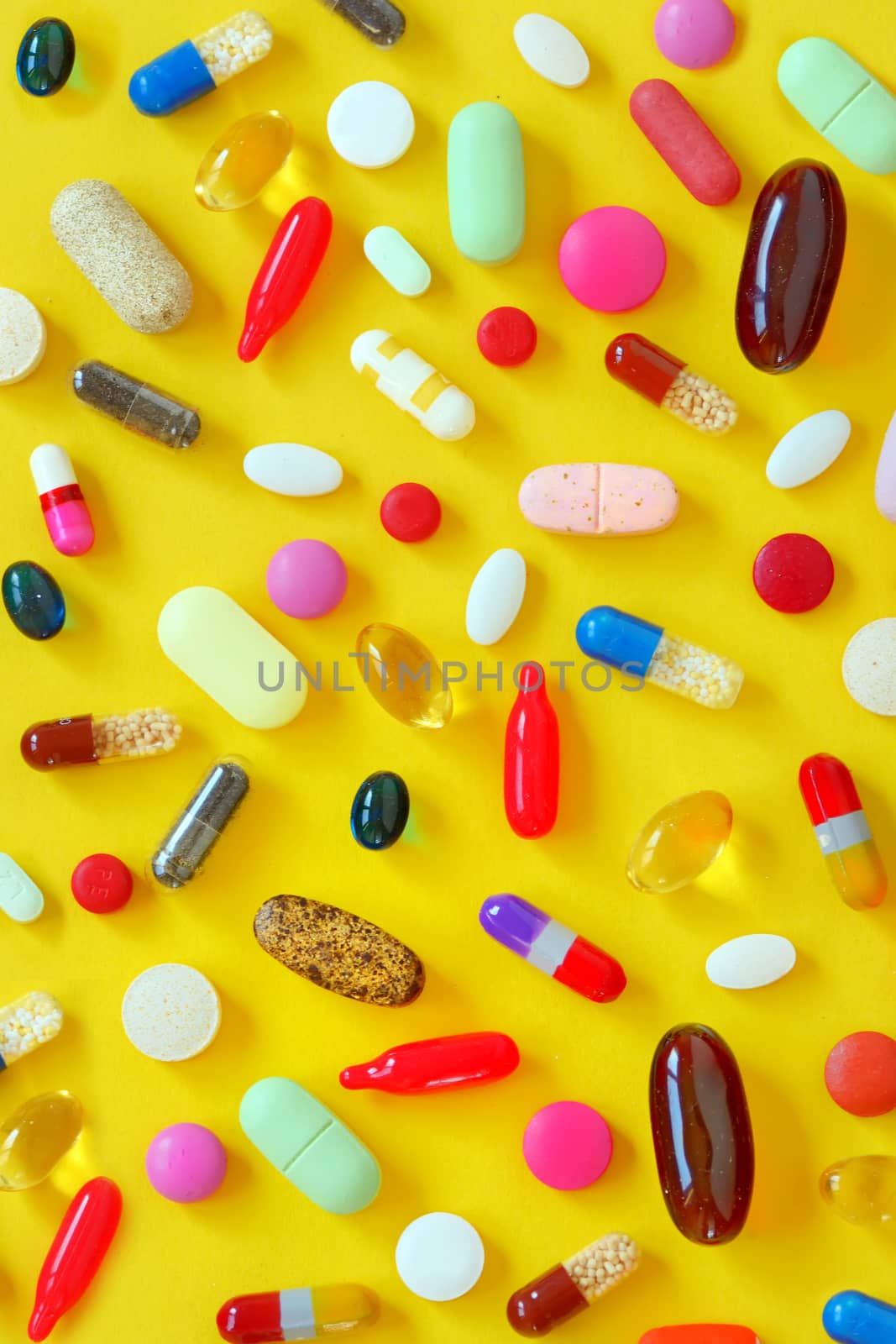 Many colorful pills on yellow background