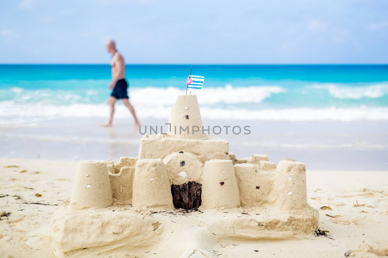 Cuban Sandcastle with the country Flag on one of the most Beautiful Beach of Cuba with a tourist in background