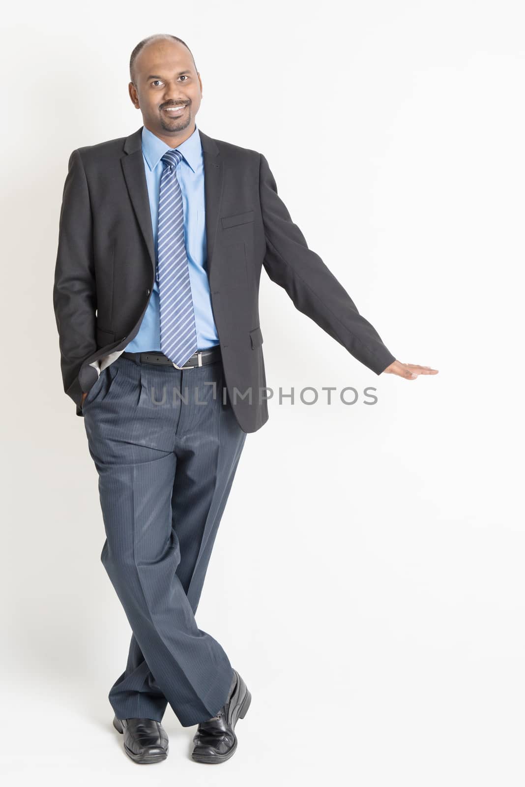 Full body Asian Indian businessman putting hand on invisible banner over plain background