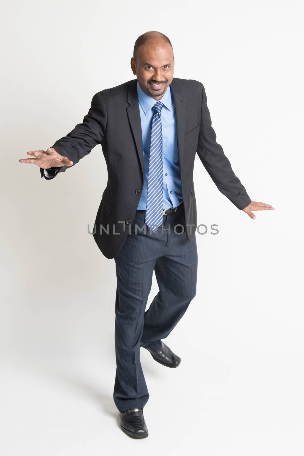 Full body Indian businessman walking balance , front view on plain background.