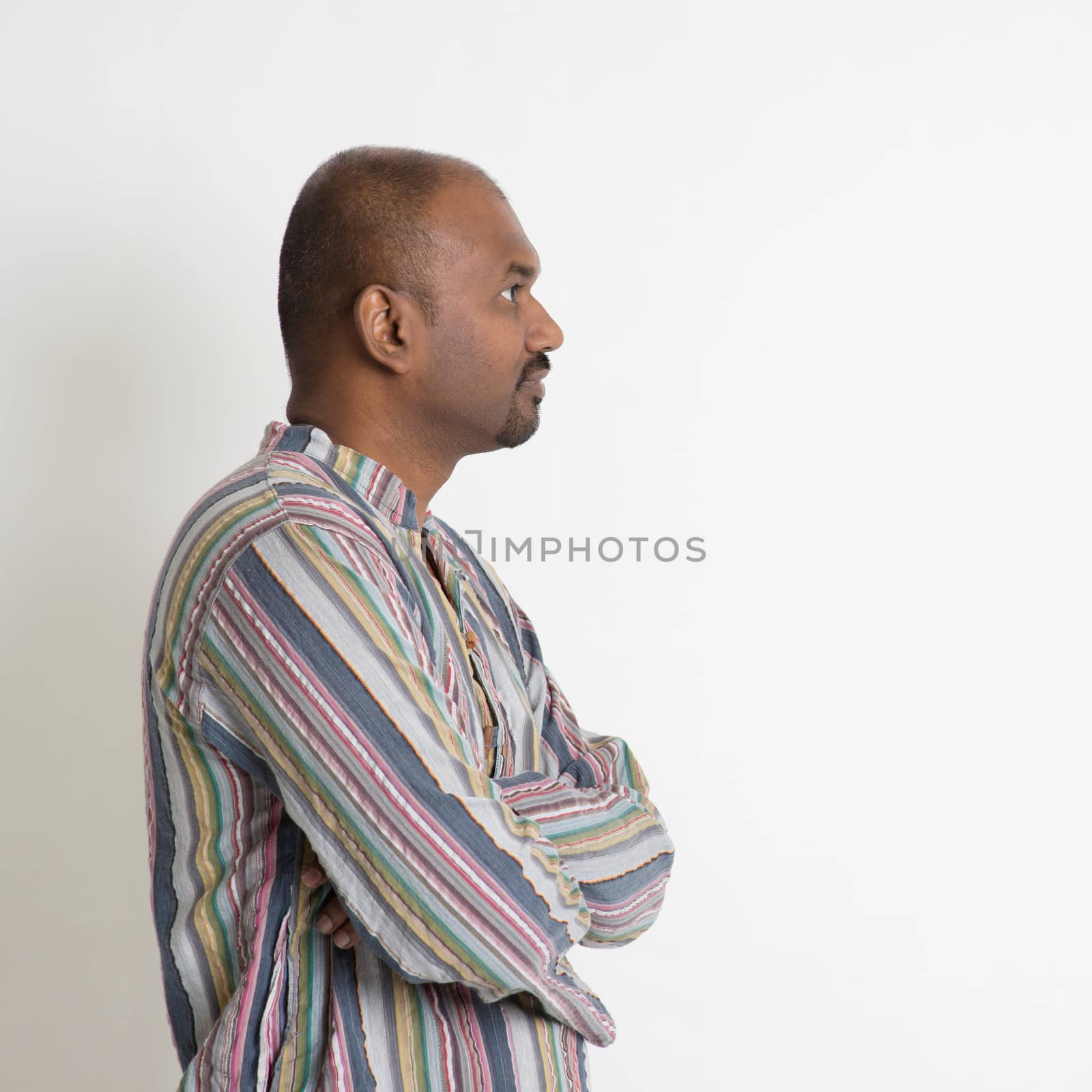 Profile of Indian male looking at blank copy space having a thought on plain background.