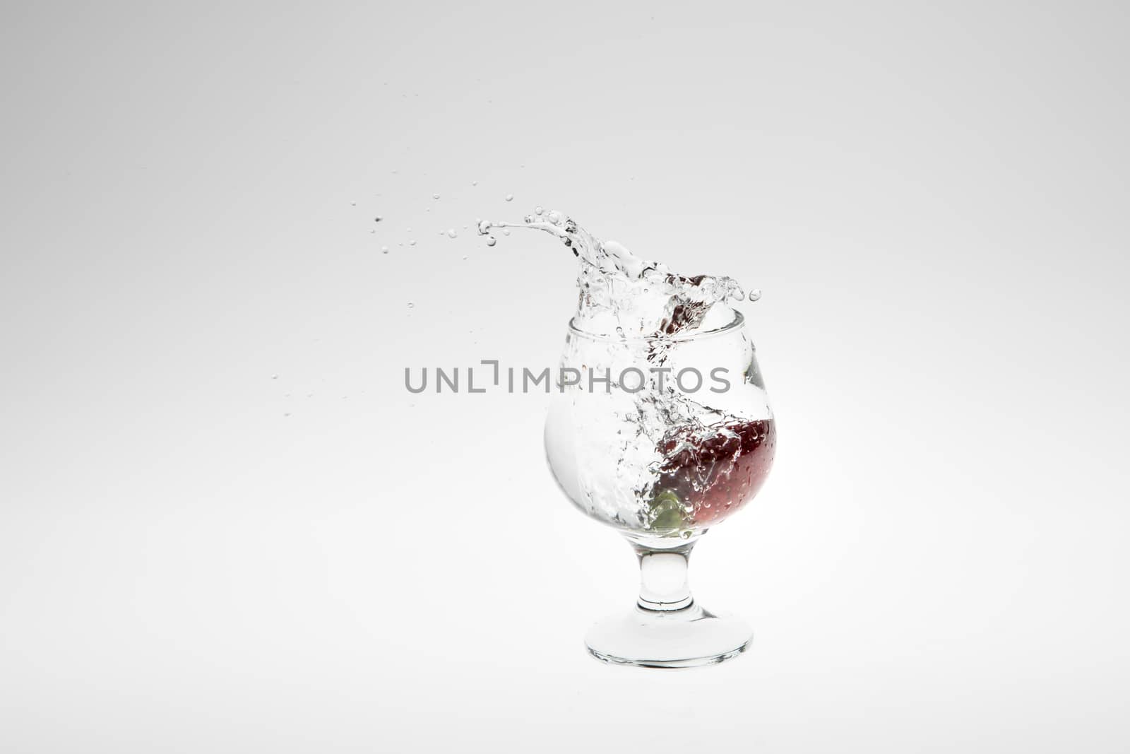 Red strawberry inside flowing water on white background