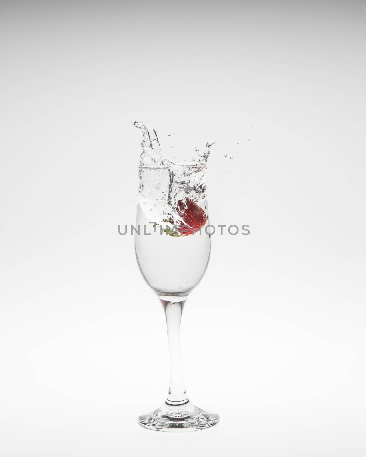 fresh strawberry dropped into water with splash on white backgrounds