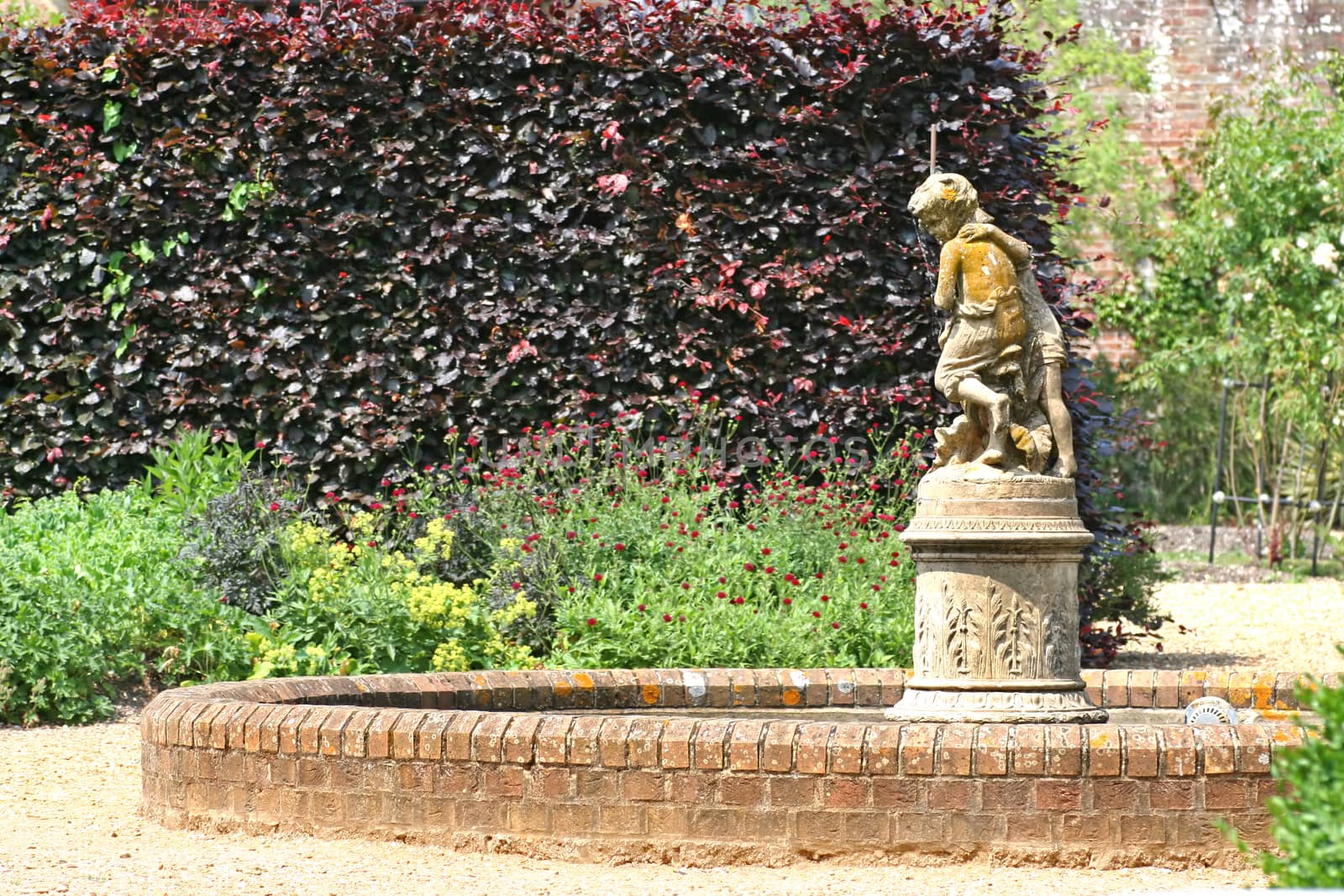 A statue in a garden with a small pond around it