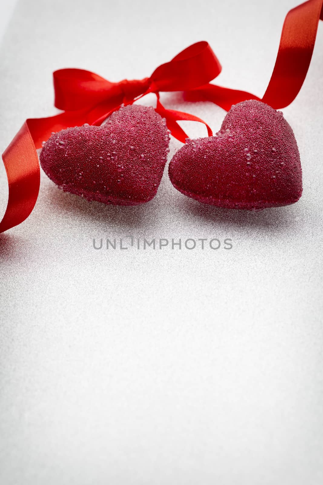 Red hearts tied with a ribbon on a silver background.