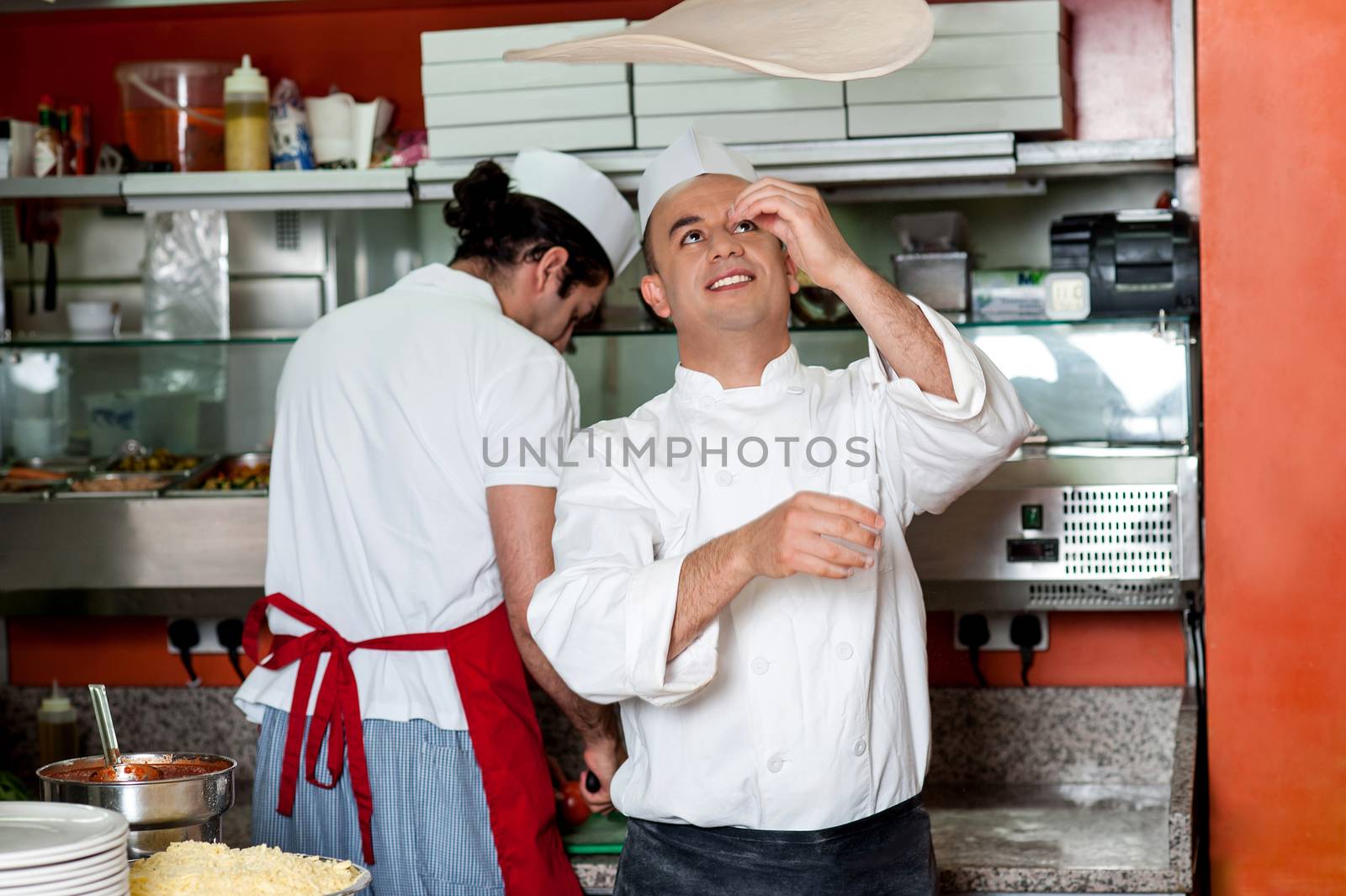 Chef throwing the pizza base dough by stockyimages