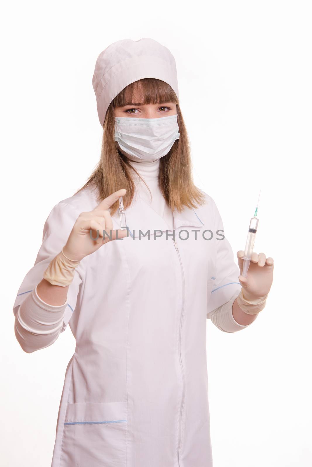 Portrait of medical worker in a white coat, hat, gloves and a mask, with a syringe and vial in hands