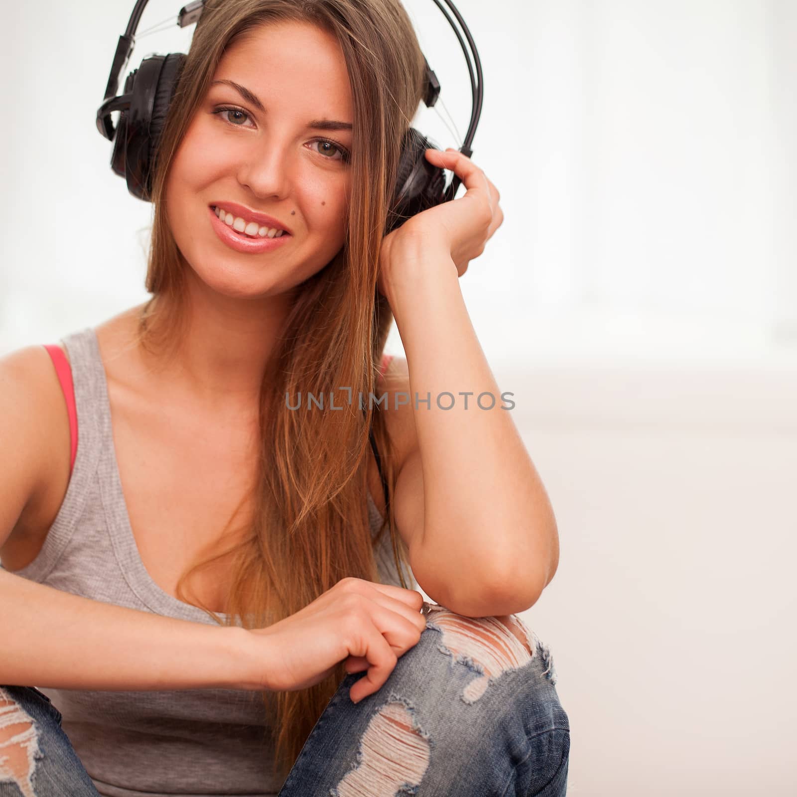 Beautiful woman enjoy music in headphones sitting on a floor