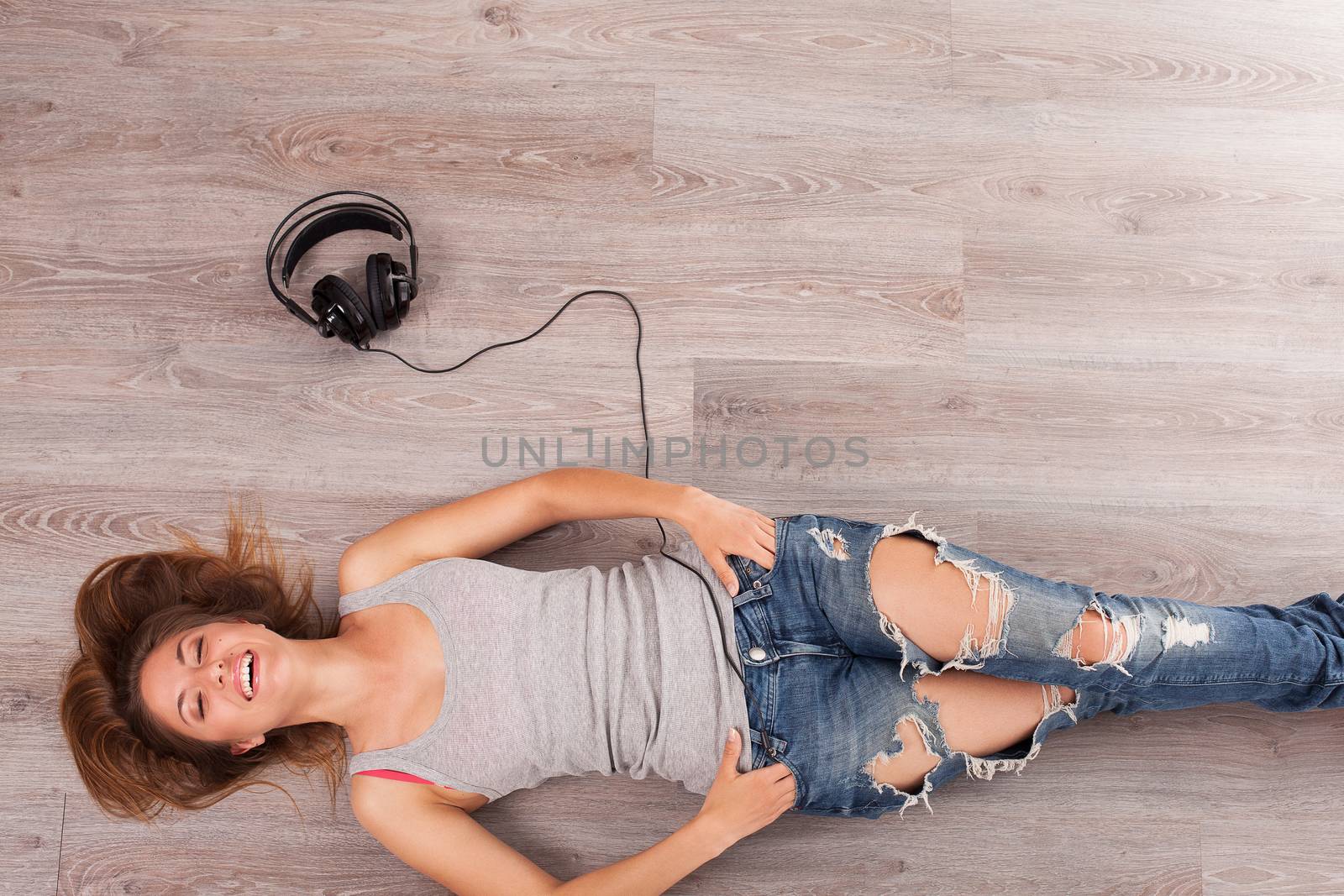 Beautiful woman with headphones lying on the floor by rufatjumali