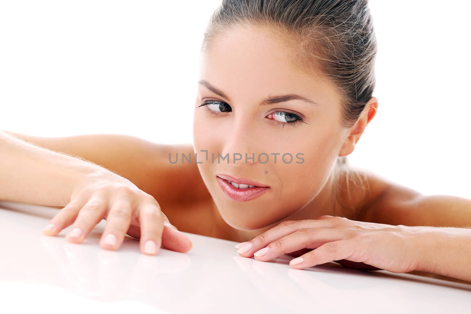 Portrait of a beautiful girl who is lying on her arms and posing over a white background