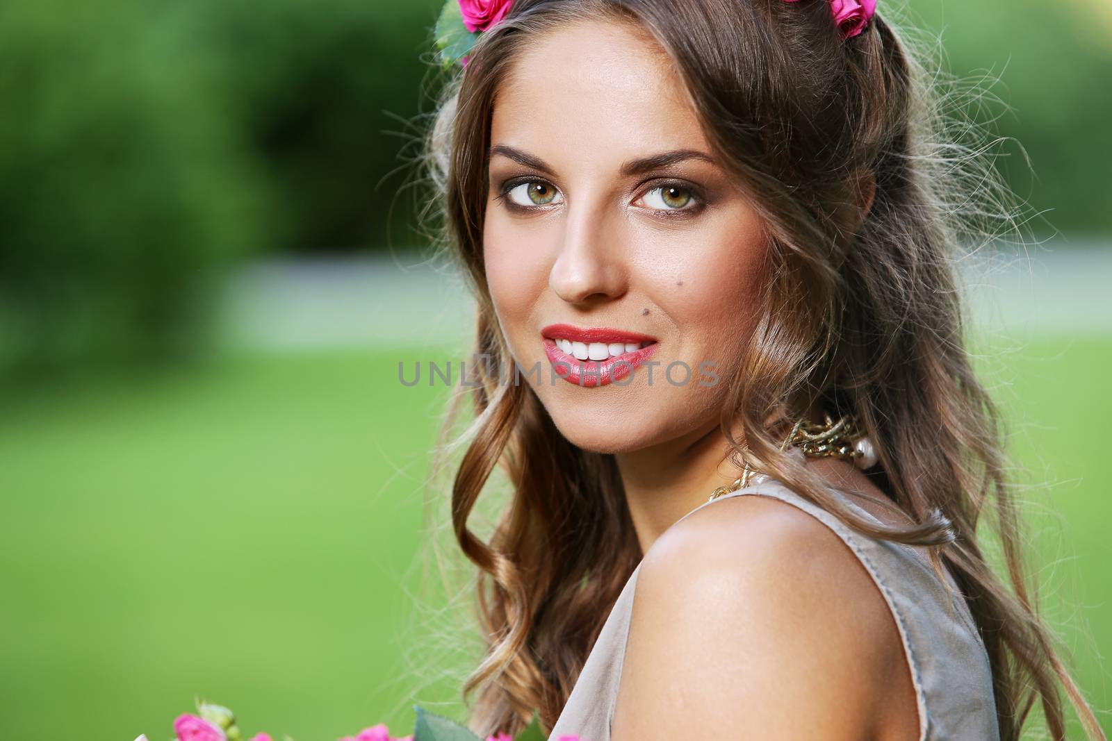Portrait of a beautiful girl holding bouquet of flowers in the park
